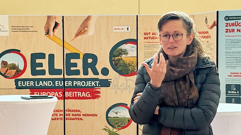 Das Bild zeigt eine Frau vor einer Ausstellungswand.