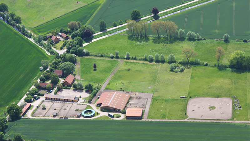 Luftbild, das einen großen landwirtschaftlichen Betrieb mit vielen Gebäuden und Weideland enthält.