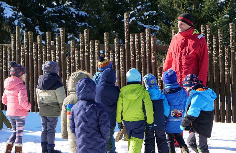 Das Bild enthält eine Gruppe von Kindern mit einem Projektleiter bei einer Bildungsveranstaltung.
