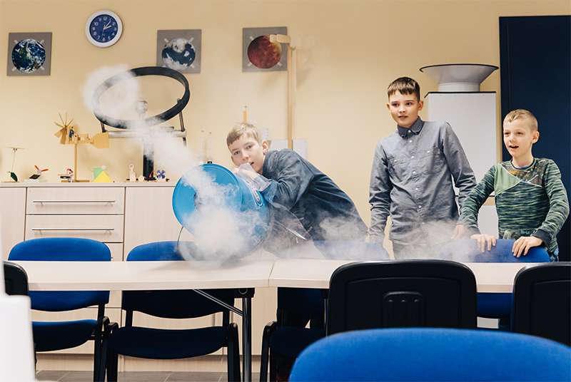 Das Bild enthält drei Schüler bei einem Wetterexperiment