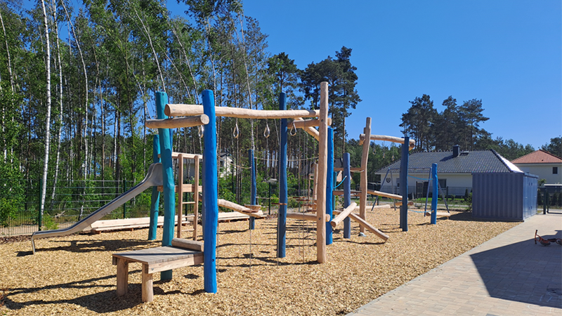 Das Bild enthält einen neu erbauten Spielplatz mit vielen Holzelementen.