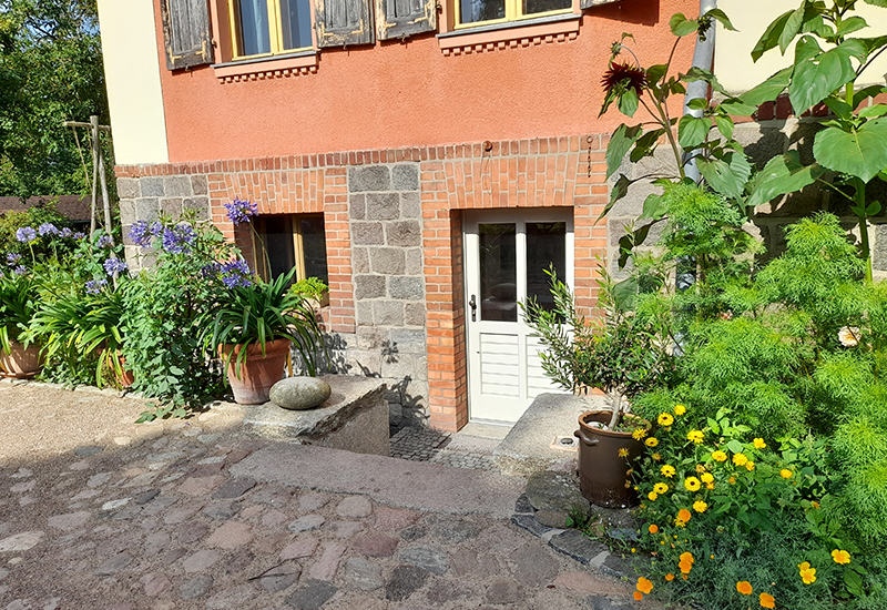 Das Bild enthält ein frisch saniertes Gebäude mit Blick auf den Eingang ins Souterrain.